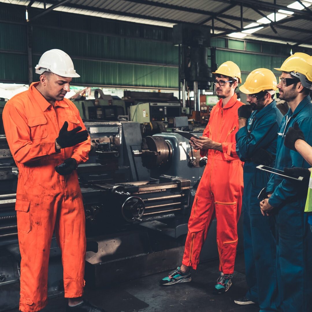 Group of apprentices working with their manager in a factory