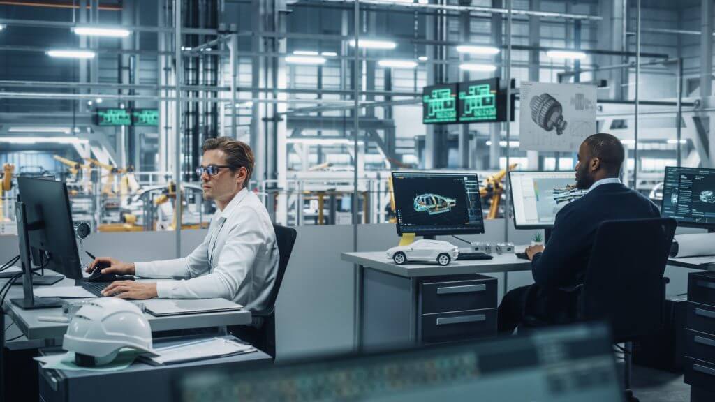 Team of Automotive Engineers Working on Desktop Computers in Modern Office at Car Assembly Plant. Industrial Product Designer Developing Electric Engine Parts with Colleagues at Vehicle Factory.
